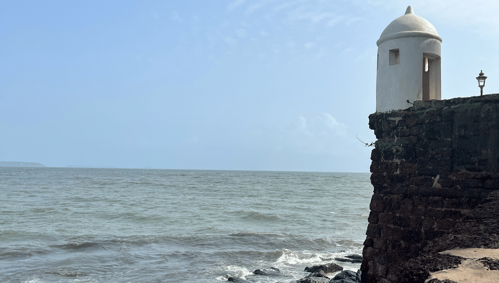 View of a seaside fort with a lighthouse tower overlooking the sea waves.